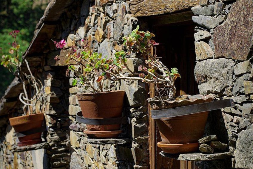 A stone building with terracotta pots hanging from the windows. 5