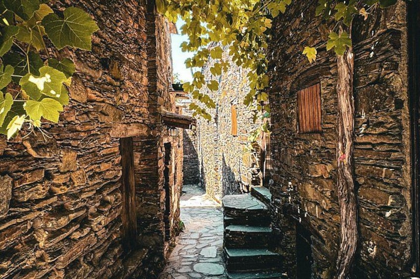 A narrow stone pathway flanked by rustic stone walls, leading to a wooden door. 2