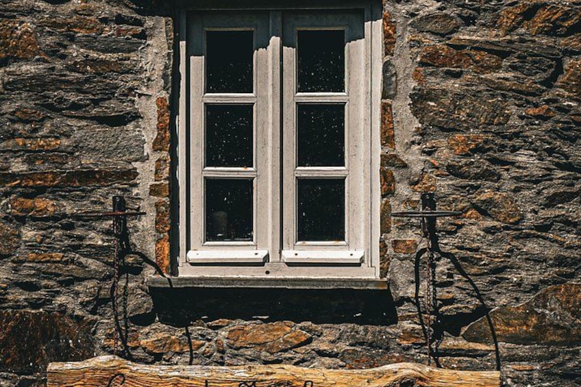 A stone building with a window and a wooden beam below it. 4