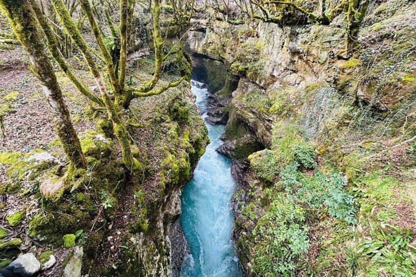 Eine schmale Schlucht, durch die ein Fluss fließt, umgeben von felsigen Klippen und Vegetation. 5