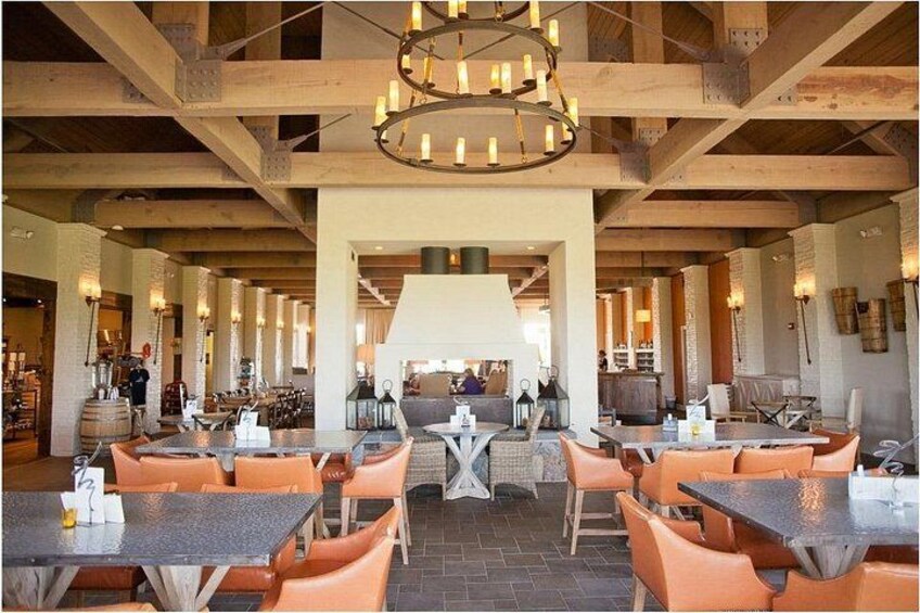 A restaurant with wooden beams, orange chairs, and tables. 2