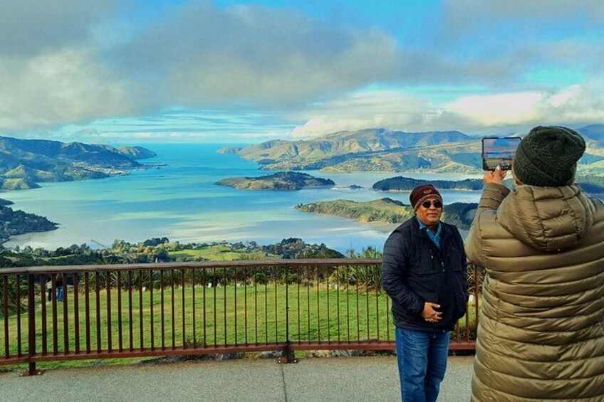 A person taking a photo of a scenic landscape with hills and a body of water. 2