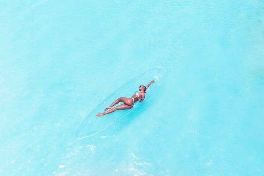 A person floating on a clear blue water surface. 1