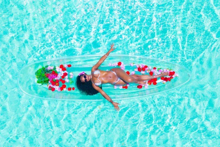 A person floating on a clear blue pool with a floral arrangement. 2