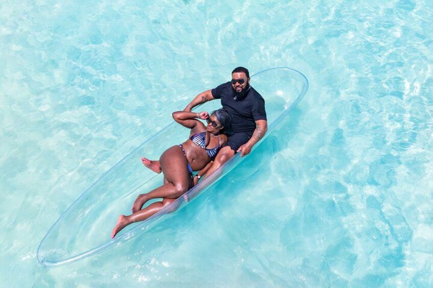 Two people floating on a clear blue inflatable raft in a pool. 2