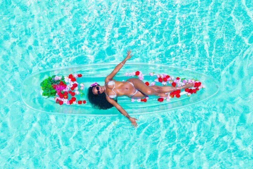 Una persona galleggia su un cerchio gonfiabile trasparente in una piscina turchese con fiori. 3