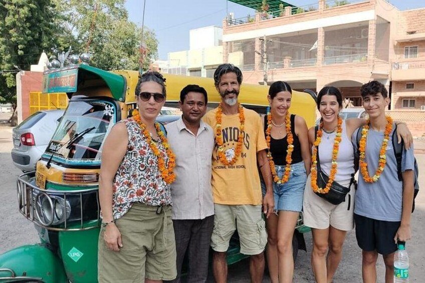 A group of people posing in front of a tuk-tuk and a building. 1
