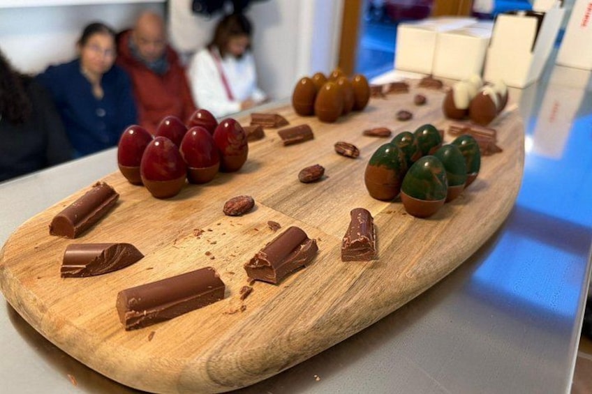 Una tabla de madera con diversas formas de chocolate y una porción de pastel de chocolate. 2