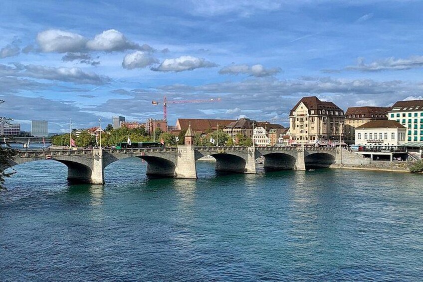 Un río con un puente de piedra, edificios y una grúa al fondo. 4