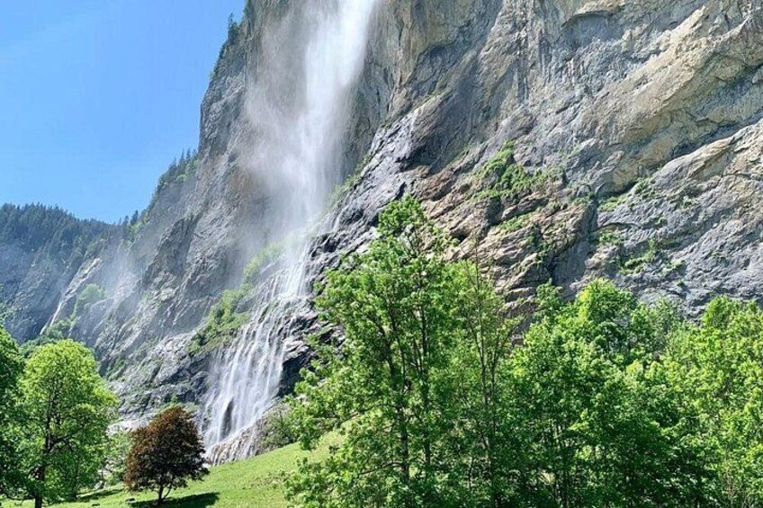 A waterfall cascading down a rocky cliff surrounded by lush green trees. 2