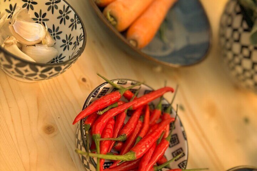 Un cuenco de chiles rojos, un cuenco de dientes de ajo y un cuenco de zanahorias sobre una mesa de madera. 5