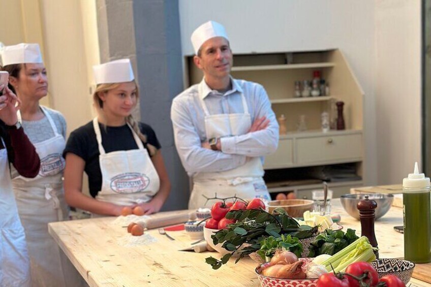 Un grupo de personas con delantales en una encimera de cocina, con verduras y utensilios de cocina. 4