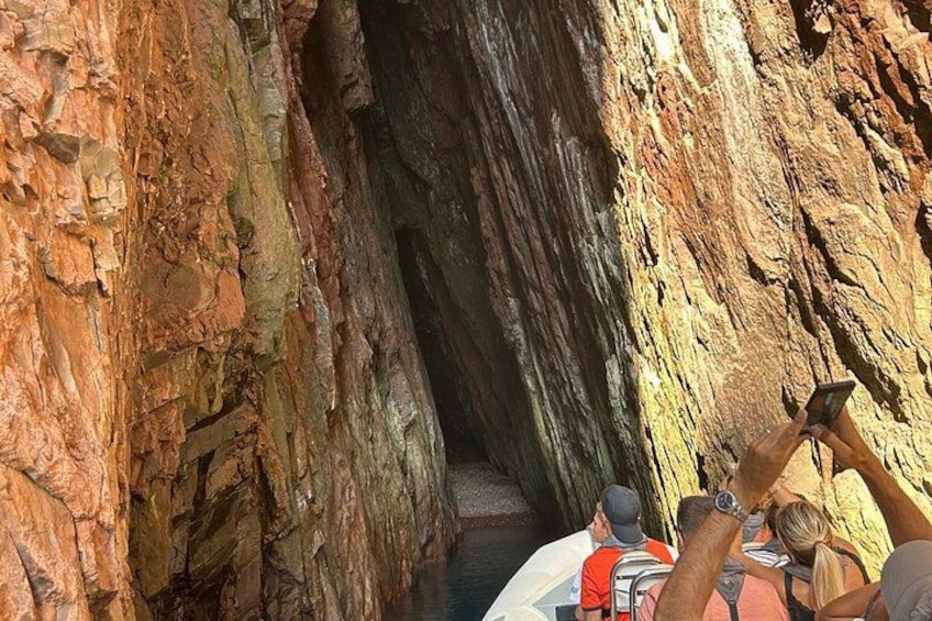 A narrow canyon with rocky walls and a group of people observing a narrow passage. 2