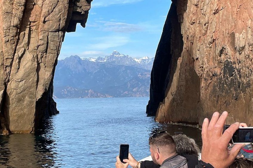 A rocky cave opening with a lake and mountains in the background. 4