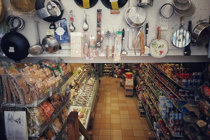 A store with shelves of packaged goods and hanging kitchen utensils. 4