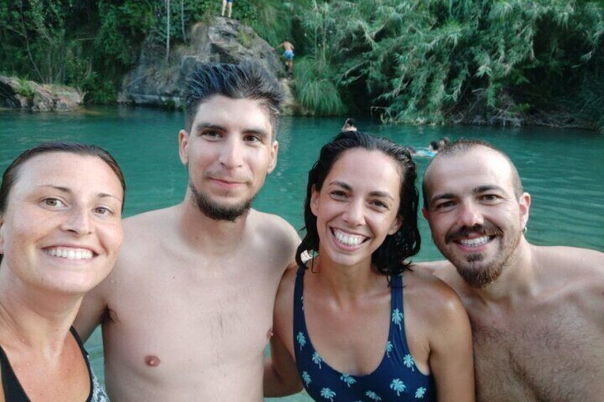 A group of people by a river with greenery in the background. 1