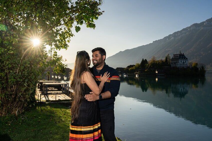 A couple embracing by a calm lake with mountains in the background. 3