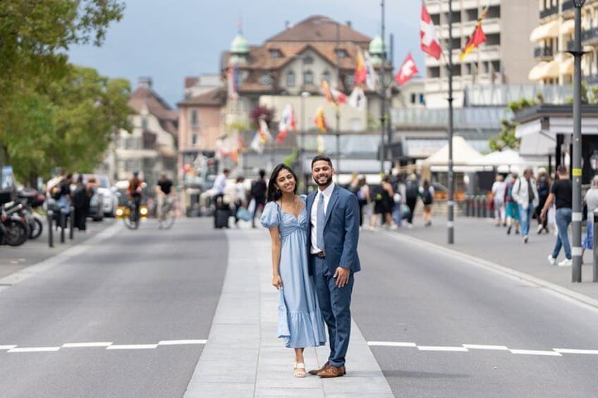 A couple standing on a city street with buildings and flags in the background. 5