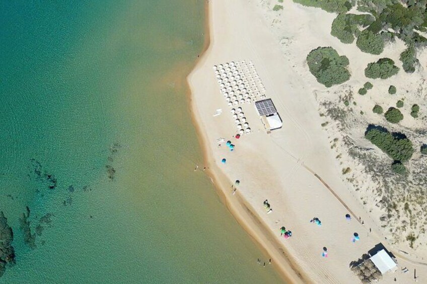 An aerial view of a beach with people, umbrellas, and a small structure. 5