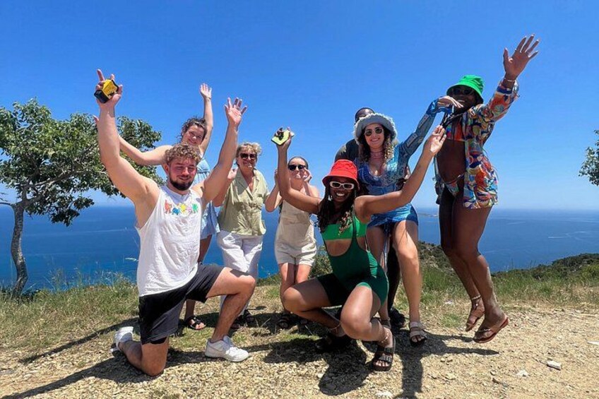 A group of people posing on a hill with a scenic view of the ocean. 3