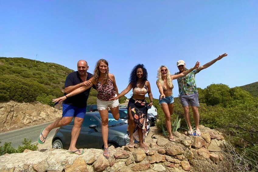 A group of people standing on a rocky outcrop with a car and a road in the background. 5