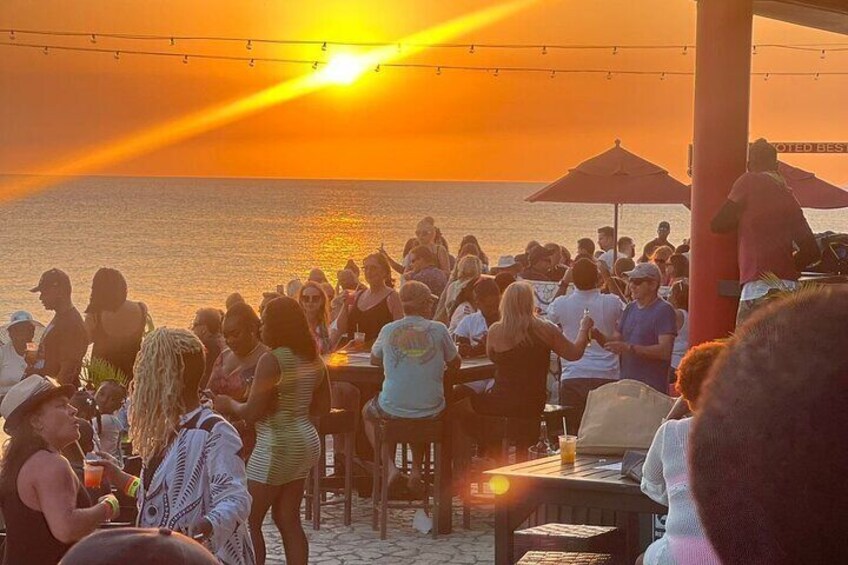 Folk samles på stranden i solnedgangen. 5