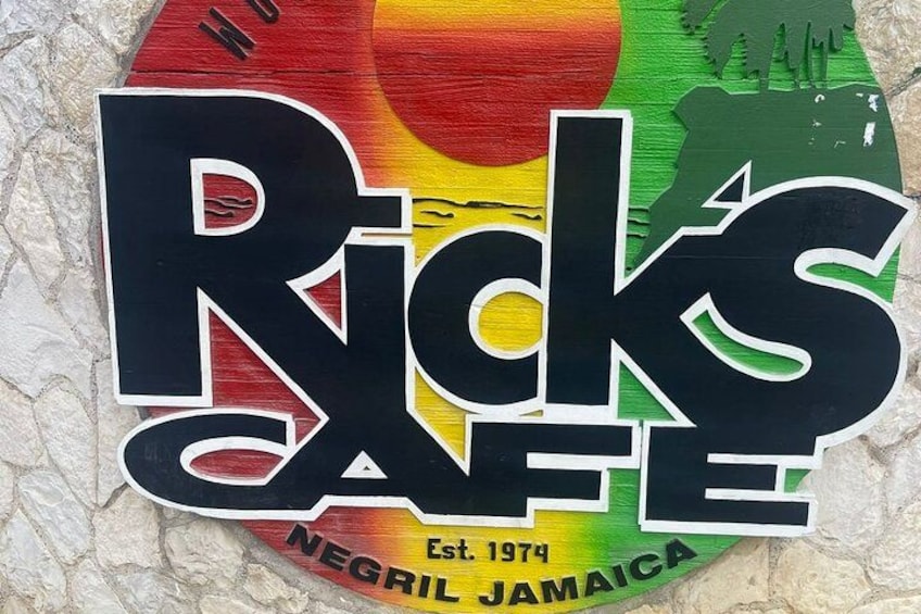 Skilt for Rick's Cafe med et farverigt design og teksten 'Etableret 1974' samt 'Negri Jamaica'. 2