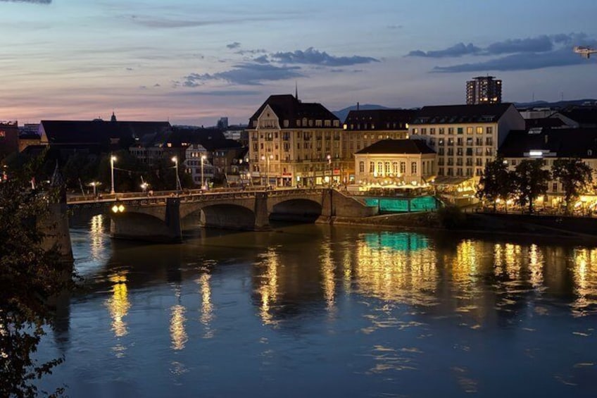 Un río con un puente, edificios y luces que se reflejan en el agua. 1