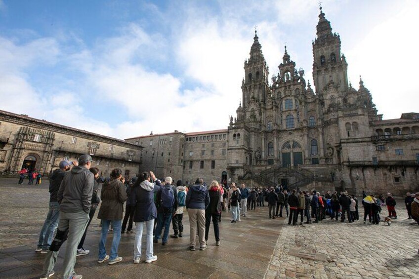 A historic building with intricate architecture, a cobblestone plaza, and a crowd of people. 2