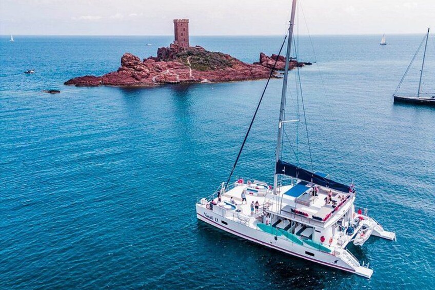 Un velero anclado cerca de una isla rocosa con una torre. 1
