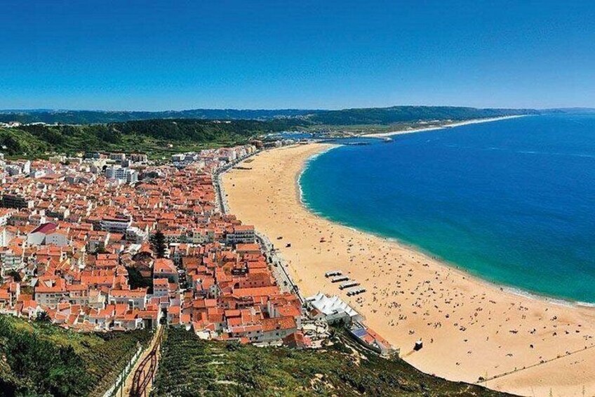 Un pueblo costero con edificios de techo rojo, una playa de arena y un mar azul cristalino. 5
