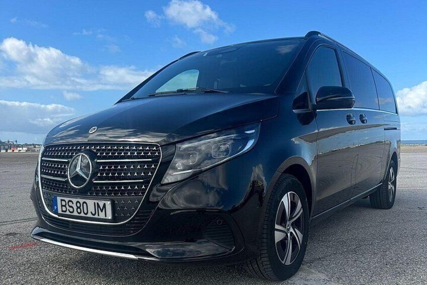 Una furgoneta Mercedes-Benz Sprinter negra estacionada sobre una superficie pavimentada, con un cielo despejado al fondo. 2