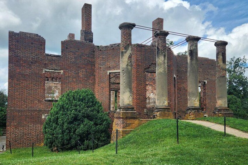Un edificio histórico de ladrillo con columnas, rodeado de césped y un sendero. 1