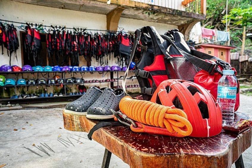 A table with various outdoor gear, including a red helmet, black shoes, and a coiled orange rope. 3
