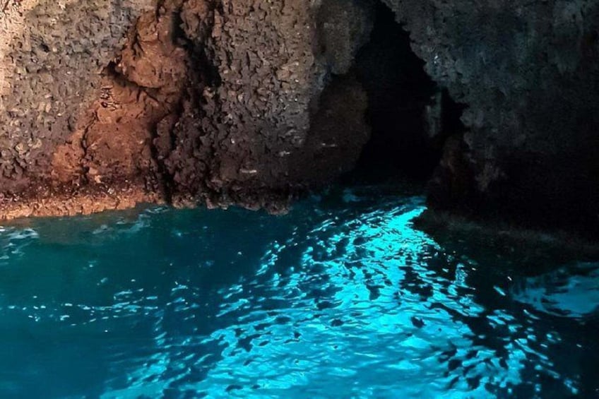 Una cueva con un estanque de agua que refleja luz azul. 5