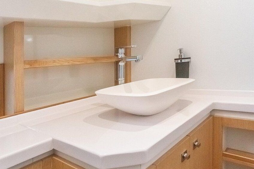 Un bagno moderno con un lavabo a incasso bianco, mobili contenitori in legno e box doccia in vetro. 2