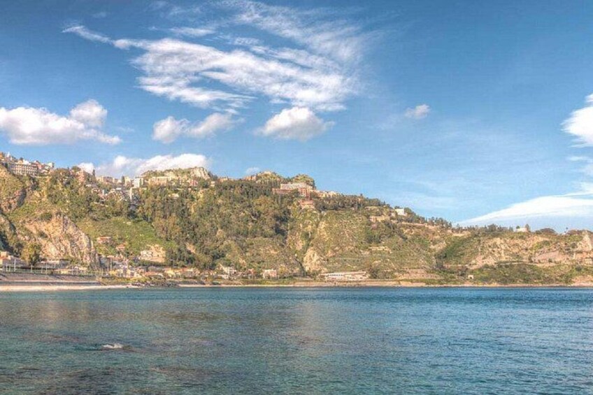 Paesaggio costiero con cielo sereno, mare calmo e un pendio con edifici. 4