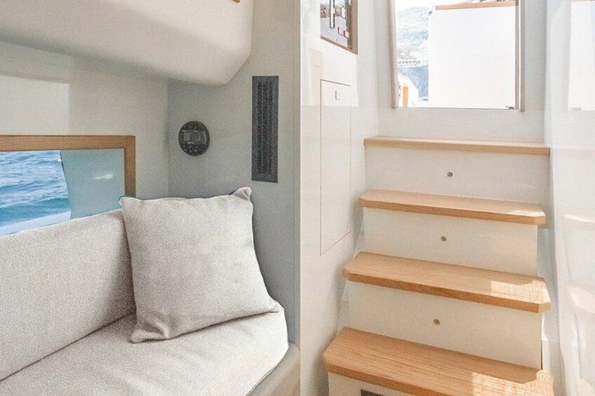 A cabin interior with a sofa, a window with a view of the sea, and wooden steps. 3