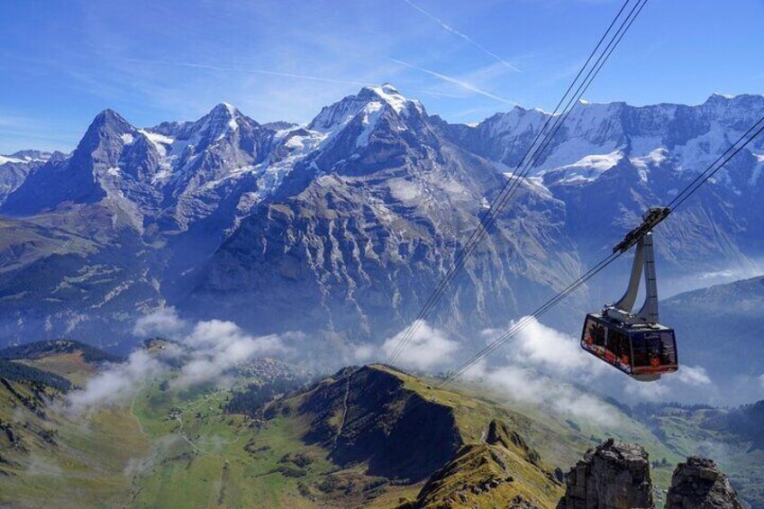 A cable car over a mountainous landscape with snow-capped peaks and green valleys. 1