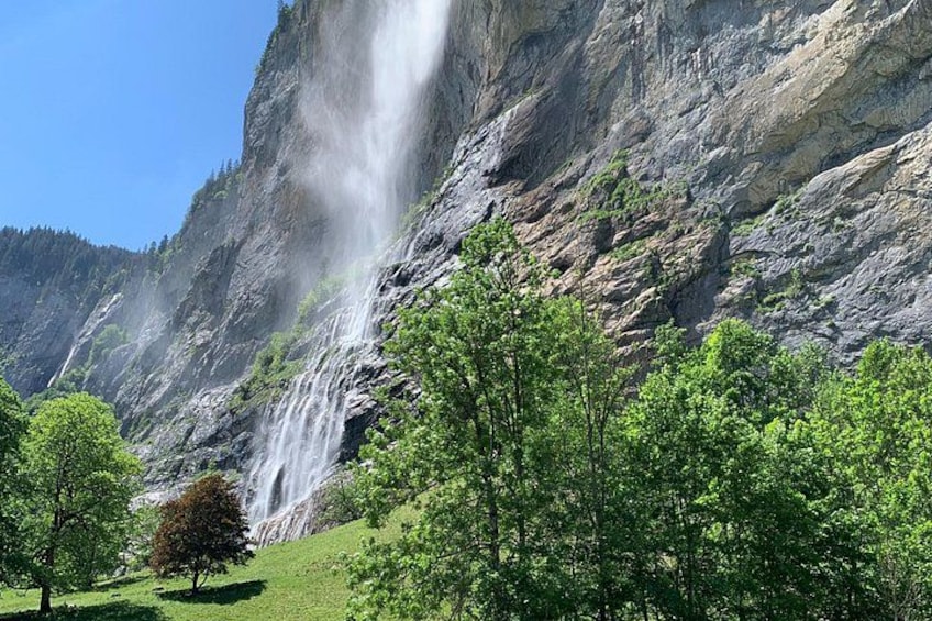 A waterfall cascading down a rocky cliff surrounded by lush green trees. 2