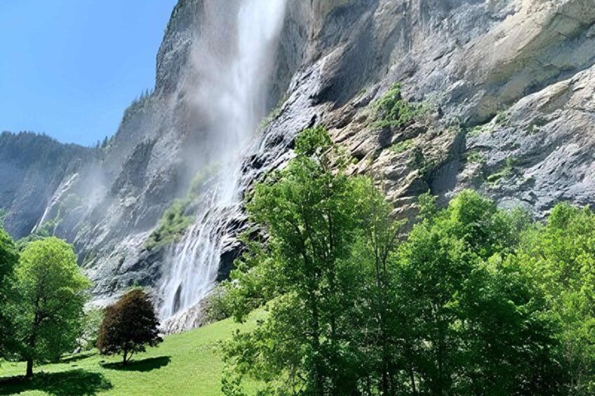 A waterfall cascading down a rocky cliff surrounded by lush green trees. 2