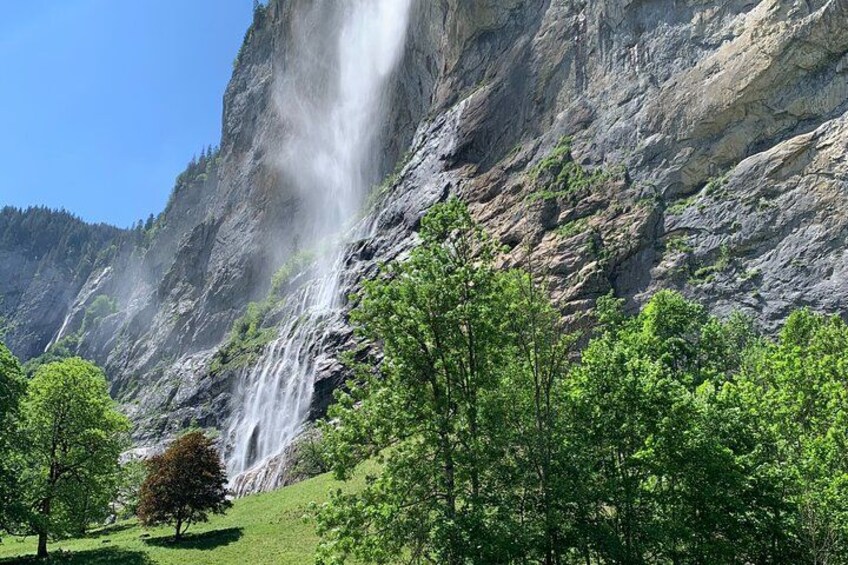 A waterfall cascading down a rocky cliff, surrounded by lush green trees. 4