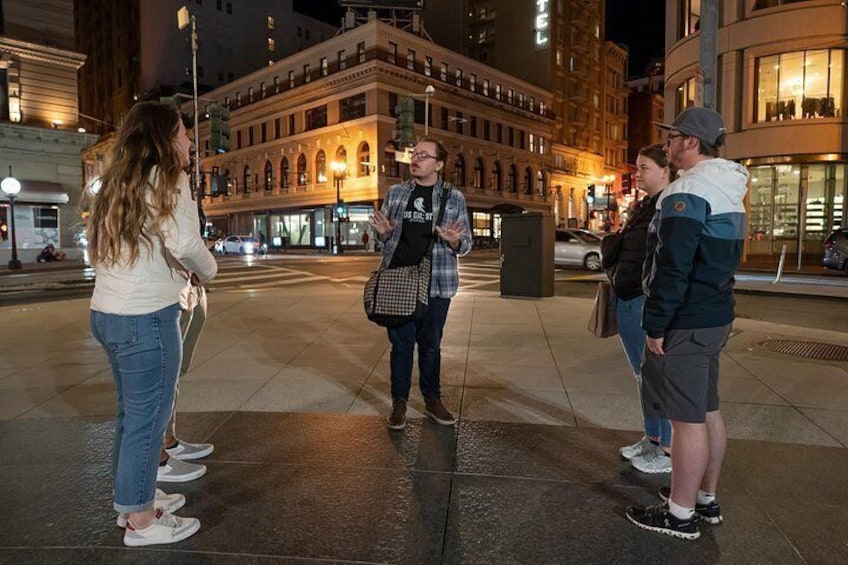 A group of people standing on a city street at night. 2