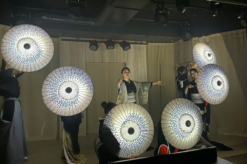 Un grupo de personas sosteniendo grandes paraguas con diseños en una habitación con poca luz. 2