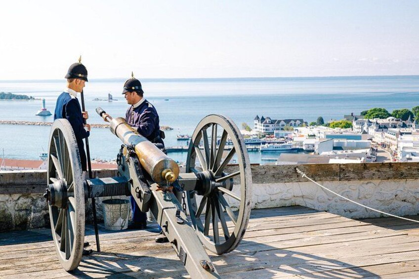 A cannon on a wooden platform overlooking a coastal town. 4