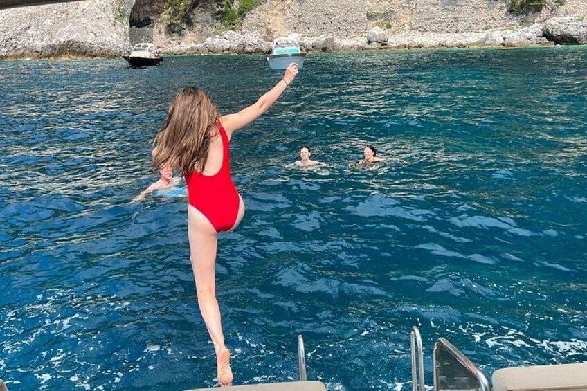 A woman in a red swimsuit jumping into a pool, with another person swimming in the background. 2