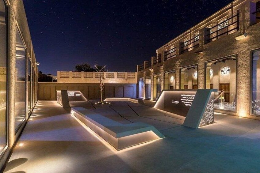 A modern building with illuminated windows and a courtyard at night. 3