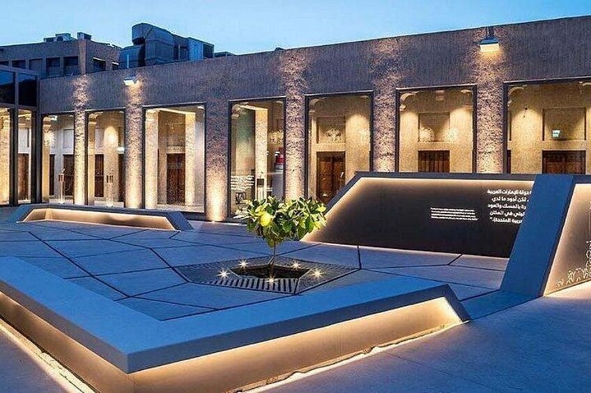 A modern building with a courtyard, columns, and a central planter with greenery. 2