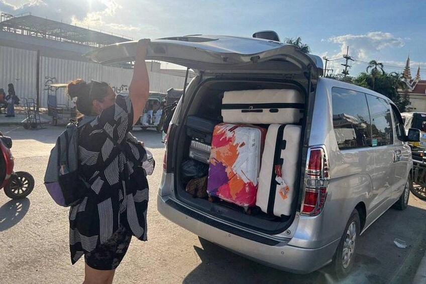 A person standing next to a van with luggage in the back. 3