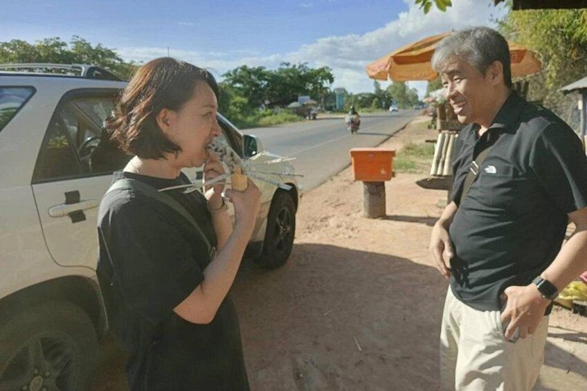 A person holding a small object, possibly a toy, and another person standing beside a vehicle. 2